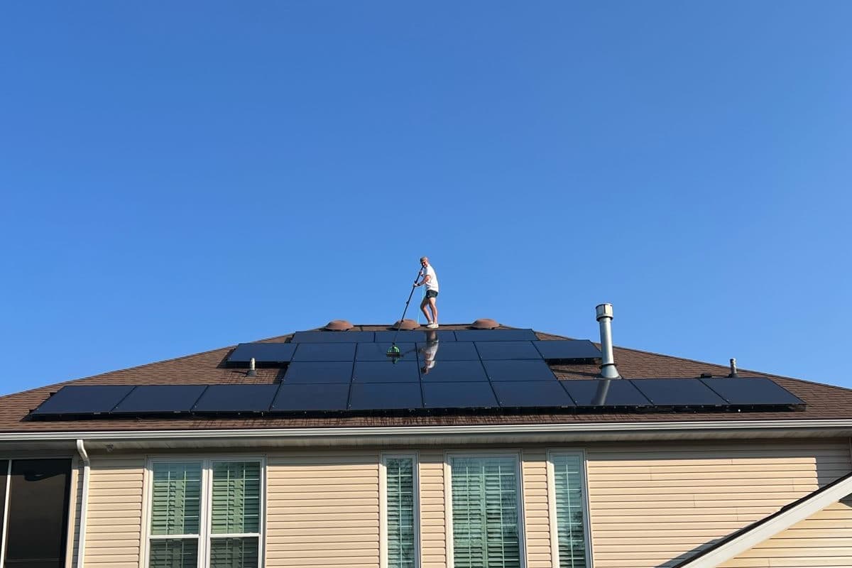 Roof-mounted solar panels on a home, with clean glass reflecting the sky